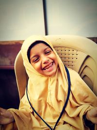 Portrait of happy girl sitting on chair at home