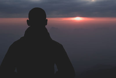 Silhouette man standing on mountain against sky during sunset