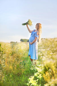 Rear view of woman standing on field against sky