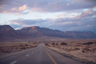 Road leading towards mountains against sky