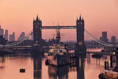 Bridge over river in city against sky during sunset