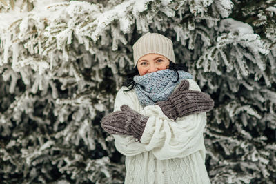 Woman in warm clothing standing against trees during winter