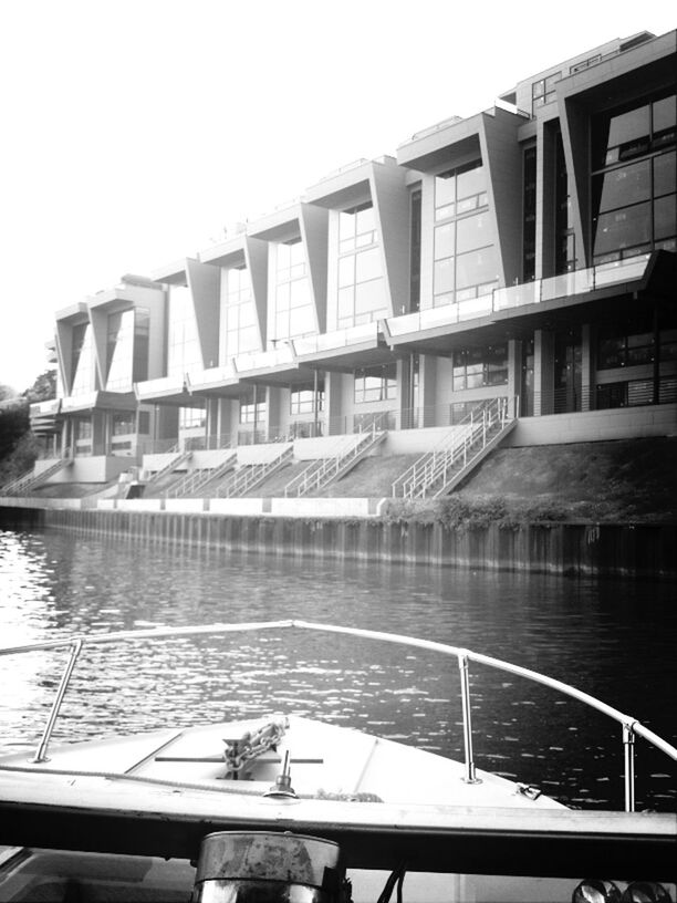 architecture, built structure, building exterior, water, clear sky, railing, reflection, city, day, river, building, canal, outdoors, sky, bridge - man made structure, residential building, no people, modern, sunlight, residential structure