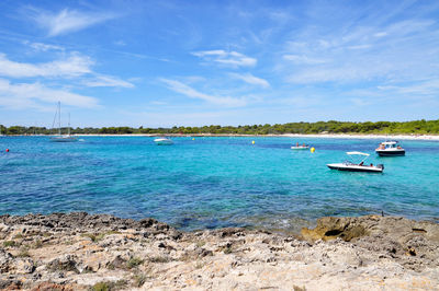 Boats moored in sea against cloudy sky