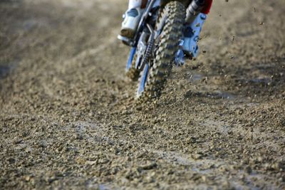 Low section of person riding bicycle on dirty road