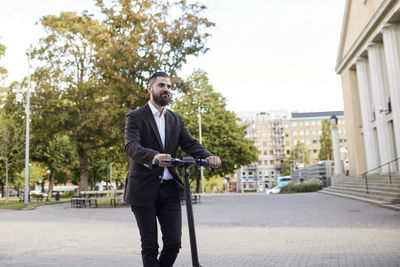 Businessman riding electric push scooter