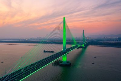 View of suspension bridge over river during sunset