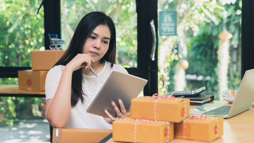 Young woman using phone while sitting on table