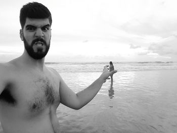 Optical illusion of furious man holding woman standing at beach