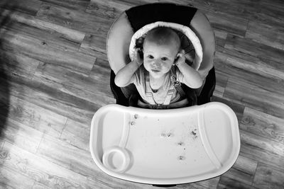 A baby boy smiles while eating a snack at home. 