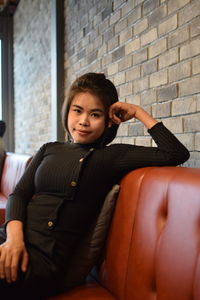 Portrait of young woman sitting on sofa in cafe