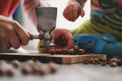 Close-up of hands breaking nuts with hammer