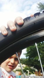 Close-up of boy holding tire of bicycle