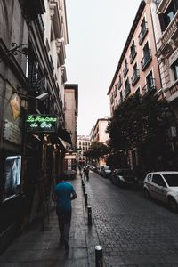 Rear view of man walking on street in city