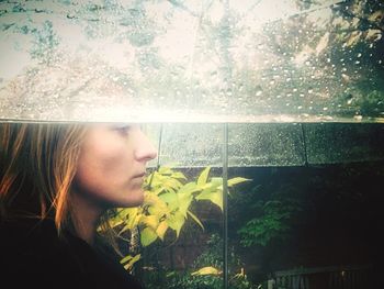 Side view of young woman looking through window