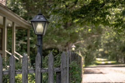 Illuminated street light on footpath by fence