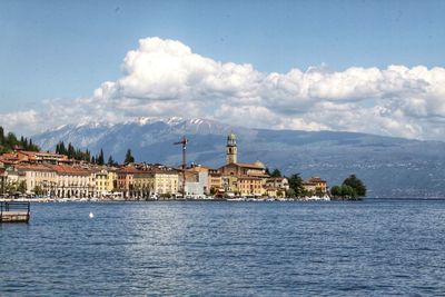 Buildings by lake against sky in city