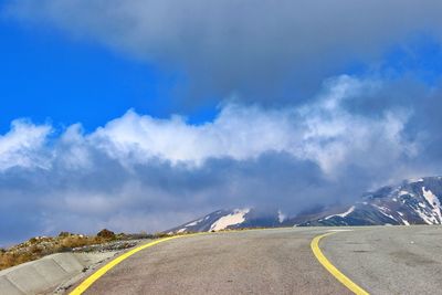 Empty road against cloudy sky