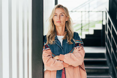 Portrait of young woman standing against building