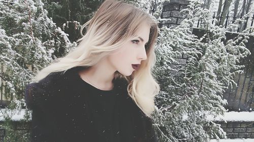 Close-up of young woman looking away during snowfall