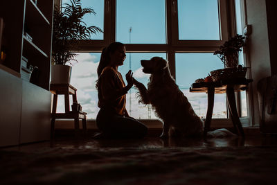 Side view of woman playing with dog at home