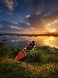 Boats moored at sea shore against sky during sunset