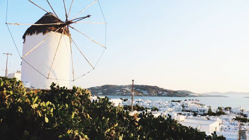 Traditional windmill by sea against clear sky