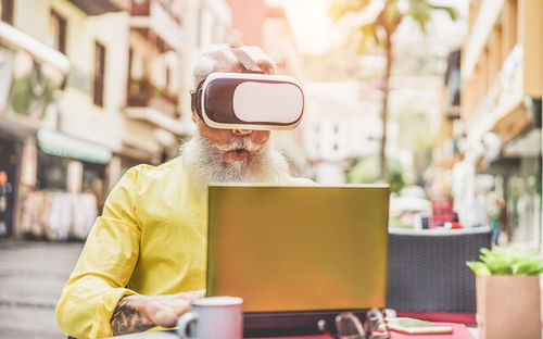 Man wearing 3d glasses while using laptop at cafe