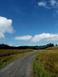 Road amidst field against sky