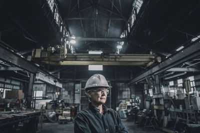 Confident female worker looking away while standing in factory