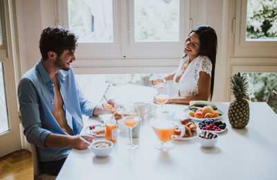 Smiling couple talking while having breakfast at dining table