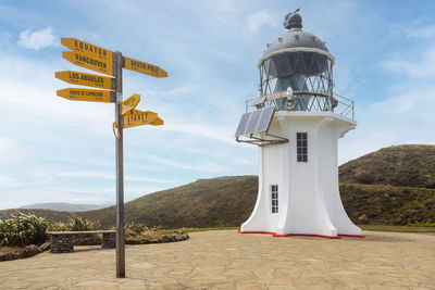 Information sign by lighthouse against sky