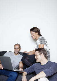 Three mid adult friends using laptop together