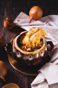 Homemade onion soup with cheese croutons in a pot on the table vertical view