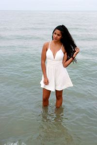 Portrait of smiling young woman standing in sea