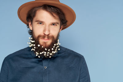 Portrait of young man standing against blue background