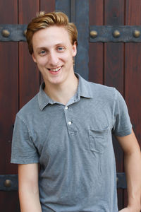 Portrait of smiling man standing against door