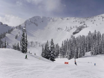 Panoramic view of people skiing on snowcapped mountain against sky