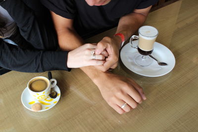 Midsection of man with coffee cup on table