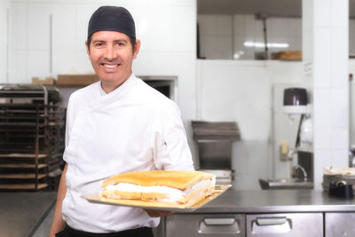 Portrait of a smiling young man preparing food in kitchen