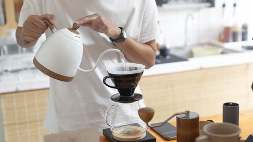 Midsection of man pouring from coffee