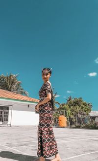 Woman standing by built structure against clear sky