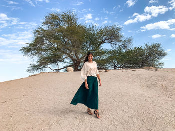 Full length of woman standing by tree against sky