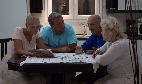 Friends talking while woman showing digital tablet at table