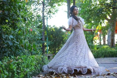 Woman standing on umbrella against trees