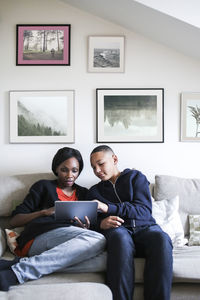 Mother and son using digital tablet on sofa at home