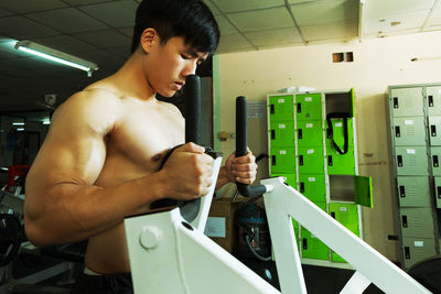 Side view of shirtless man exercising in gym