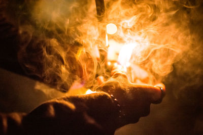 Close-up of hand holding pipe amidst smoke