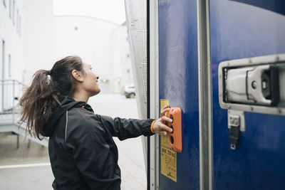 Woman looking away while pushing buttons on delivery van