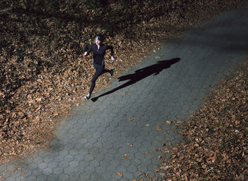 High angle view of young woman running on illuminated footpath at night